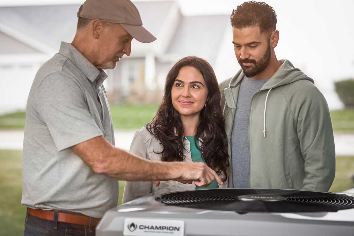 HVAC contractor conversing with home owners next to a Champion HVAC unit.